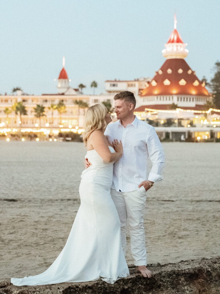 Bride and groom walking near ocean for romantic coastal blue hour wedding photos