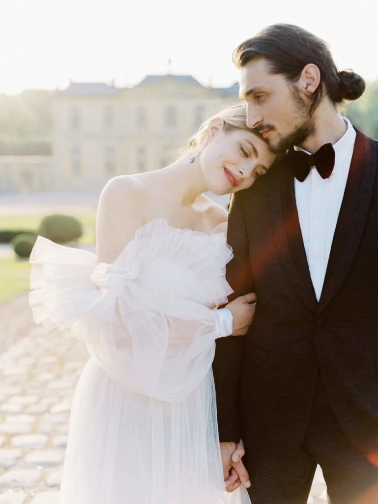 Bride and groom embracing in front of a château