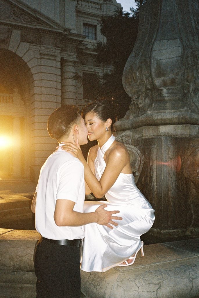 Newlyweds kissing by old city fountain luxury evening wedding photography