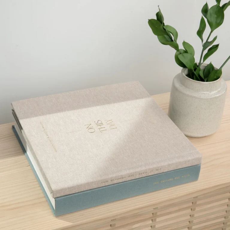 A wedding photo album on a table beside a plant